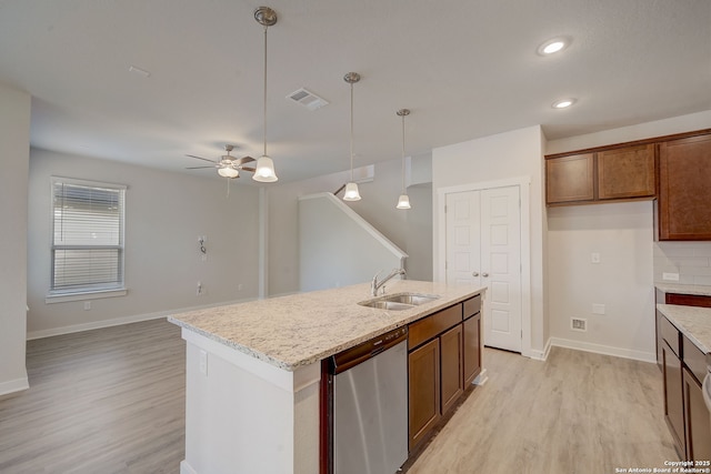 kitchen featuring sink, decorative light fixtures, a center island with sink, light wood-type flooring, and dishwasher