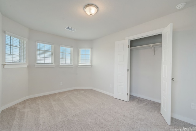 unfurnished bedroom with a closet and light carpet