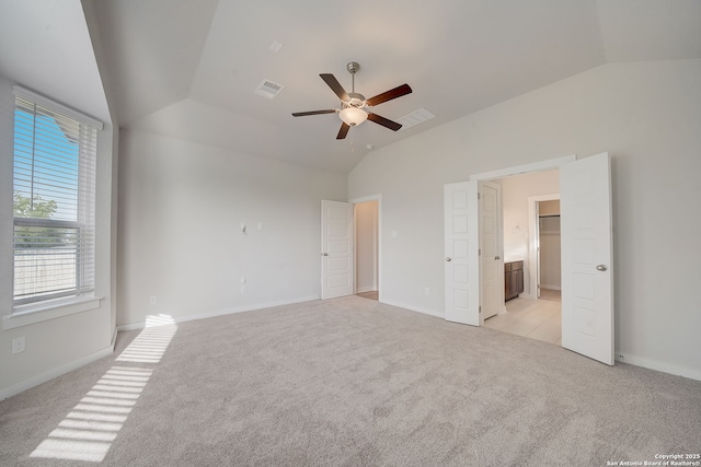 interior space featuring vaulted ceiling, light colored carpet, ceiling fan, and ensuite bath