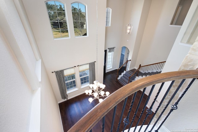 stairs with a notable chandelier, hardwood / wood-style floors, and a high ceiling