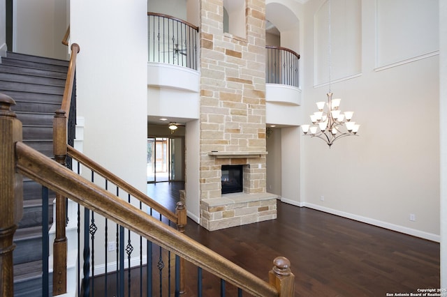 unfurnished living room featuring a towering ceiling, a fireplace, and dark hardwood / wood-style flooring