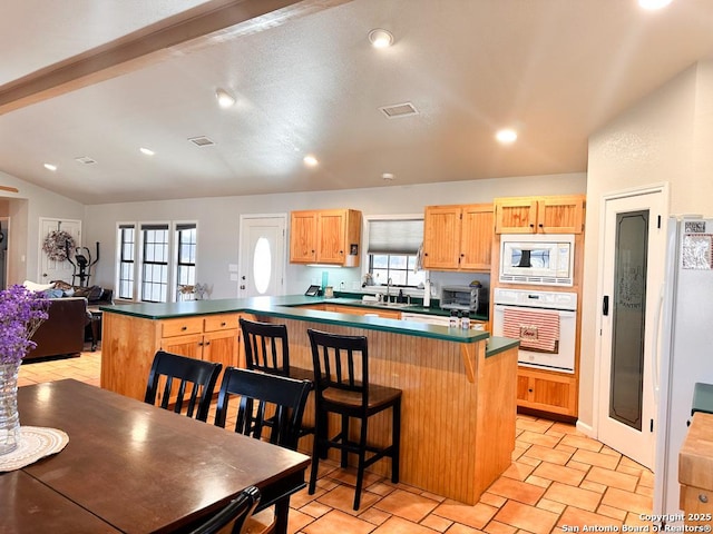 kitchen with sink, vaulted ceiling with beams, a kitchen breakfast bar, kitchen peninsula, and white appliances