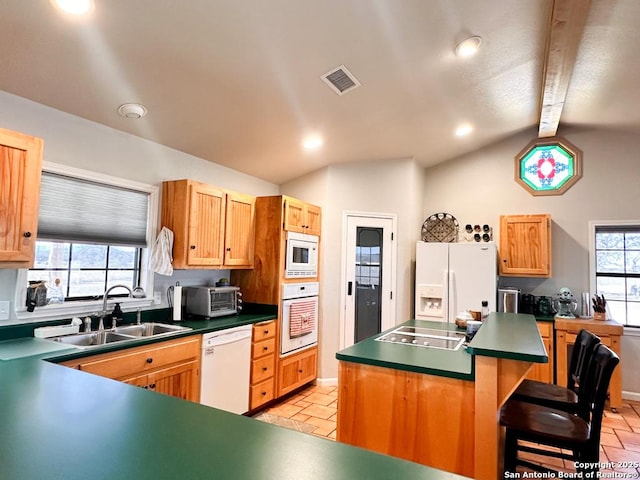 kitchen with lofted ceiling, sink, a center island, a kitchen breakfast bar, and white appliances