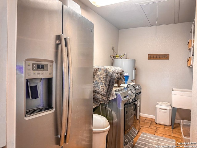 kitchen featuring water heater, stainless steel refrigerator with ice dispenser, and washer and clothes dryer