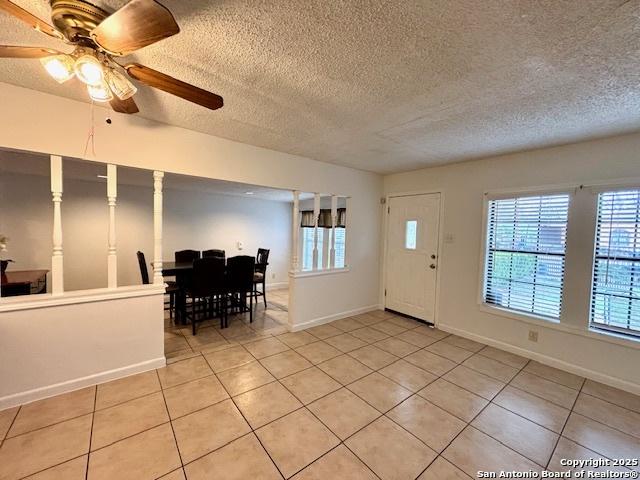 tiled foyer entrance with ceiling fan and a textured ceiling