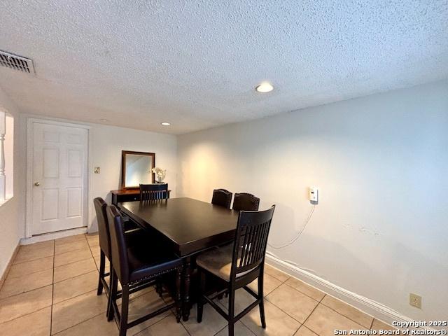 tiled dining room featuring a textured ceiling