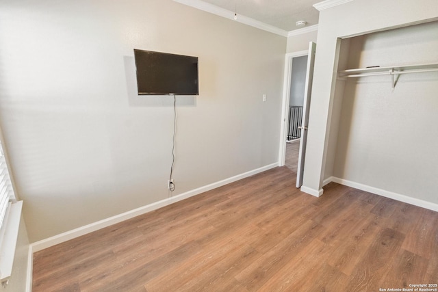 unfurnished bedroom featuring ornamental molding, wood-type flooring, and a closet