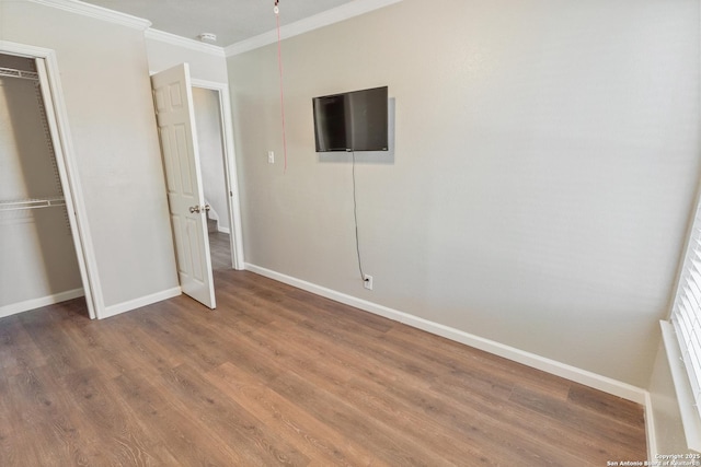 unfurnished bedroom with crown molding, hardwood / wood-style floors, and a closet