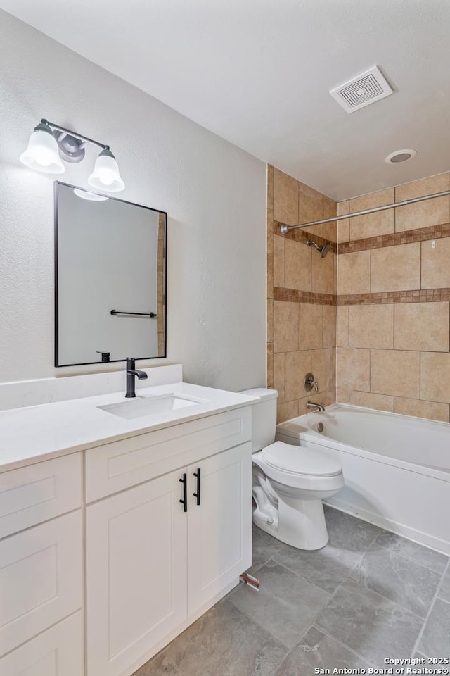 full bathroom featuring tiled shower / bath, vanity, and toilet