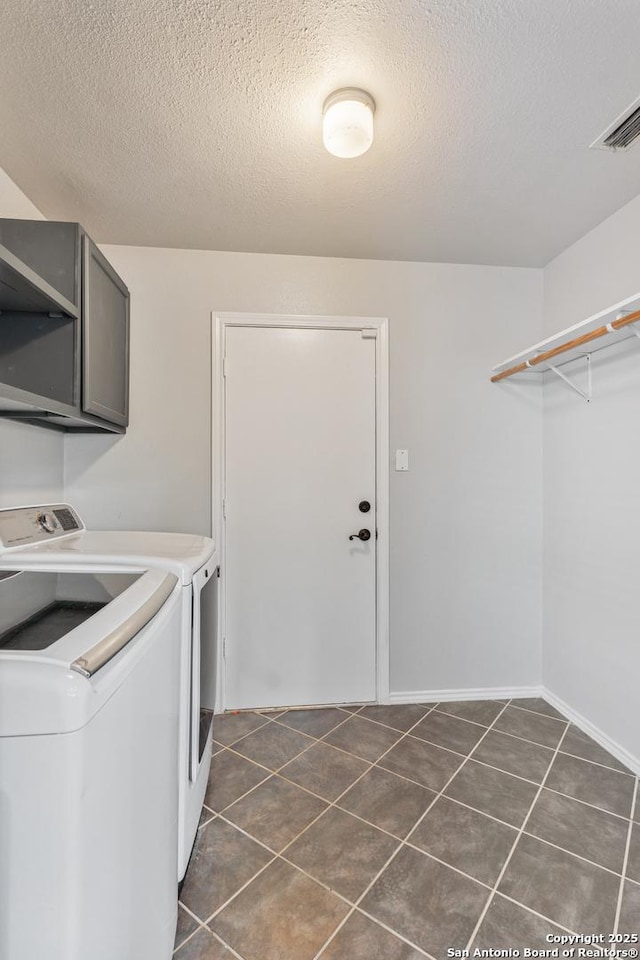 washroom with cabinets, dark tile patterned floors, washing machine and clothes dryer, and a textured ceiling