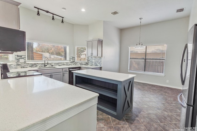 kitchen featuring sink, stainless steel refrigerator, gray cabinetry, track lighting, and decorative light fixtures