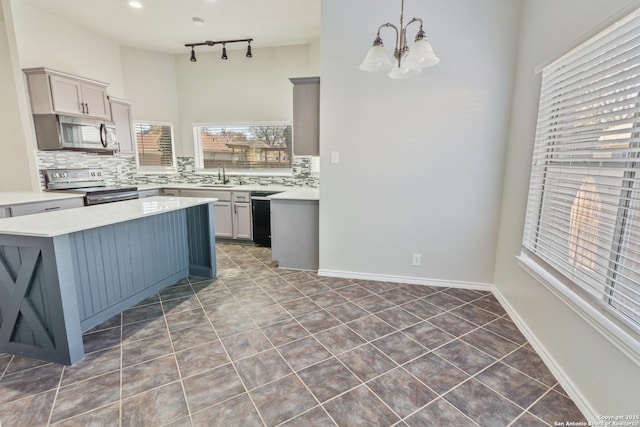 kitchen featuring stainless steel appliances, pendant lighting, track lighting, and decorative backsplash