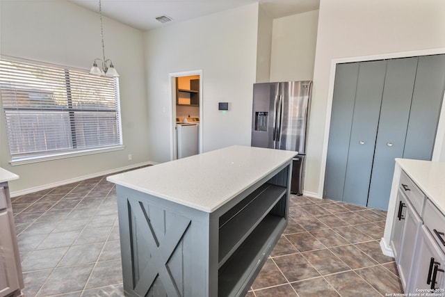 kitchen featuring a kitchen island, washer / dryer, white cabinets, hanging light fixtures, and stainless steel fridge with ice dispenser