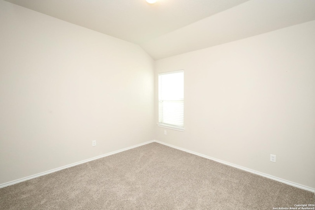 empty room with carpet floors and vaulted ceiling