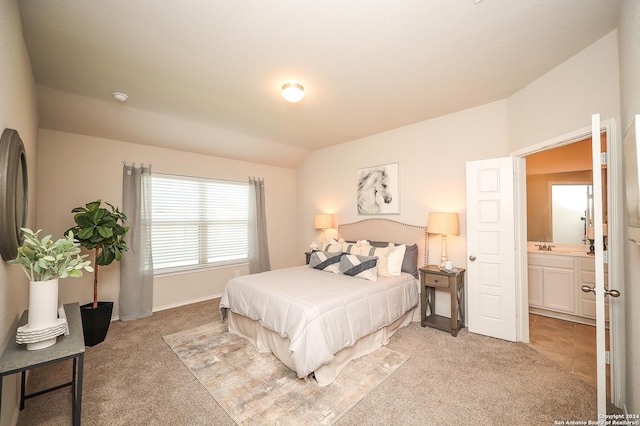 bedroom featuring ensuite bathroom, lofted ceiling, and light colored carpet