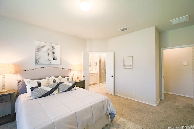 bedroom with ensuite bathroom and light carpet