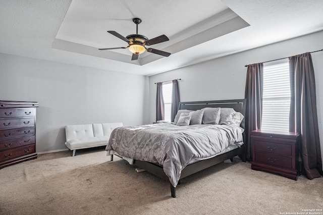 bedroom featuring light carpet, a raised ceiling, and ceiling fan