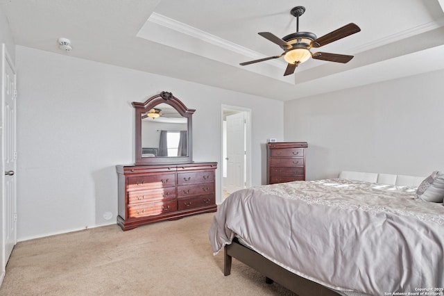 bedroom featuring a raised ceiling, ornamental molding, light colored carpet, and ceiling fan