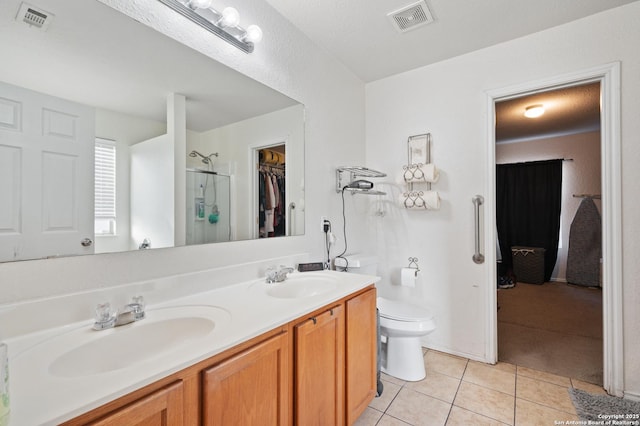 bathroom with tile patterned flooring, vanity, toilet, and walk in shower