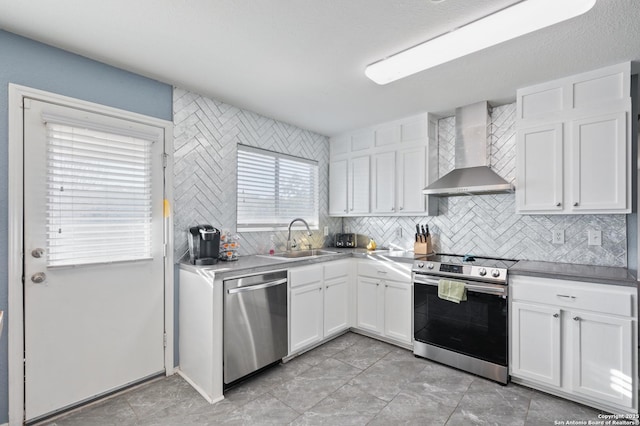 kitchen with sink, white cabinetry, backsplash, stainless steel appliances, and wall chimney exhaust hood