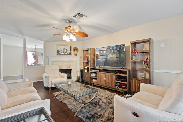 living room featuring a stone fireplace, dark hardwood / wood-style floors, and ceiling fan