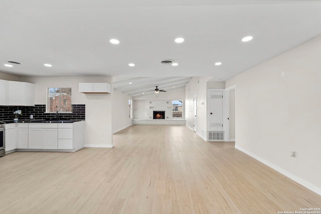 kitchen with lofted ceiling, ceiling fan, light hardwood / wood-style floors, white cabinets, and decorative backsplash