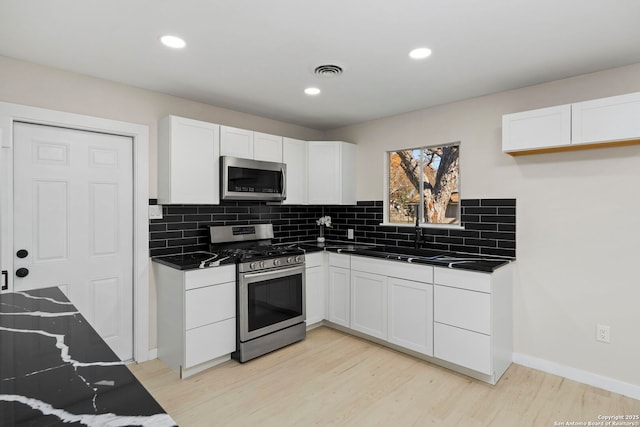 kitchen with white cabinetry, stainless steel appliances, and backsplash