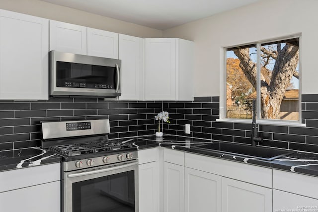 kitchen with backsplash, sink, white cabinets, and appliances with stainless steel finishes