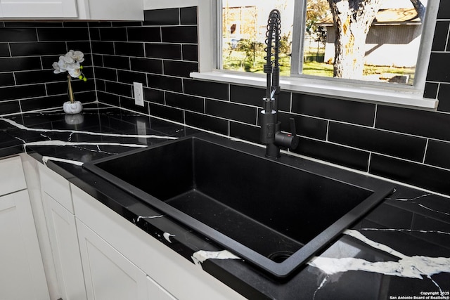 kitchen featuring sink, backsplash, and white cabinets