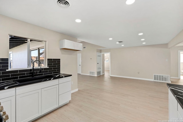 kitchen with white cabinetry, sink, backsplash, and light wood-type flooring