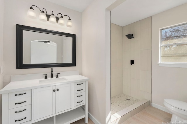 bathroom with tiled shower, vanity, toilet, and hardwood / wood-style floors