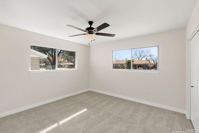 carpeted empty room with a wealth of natural light and ceiling fan