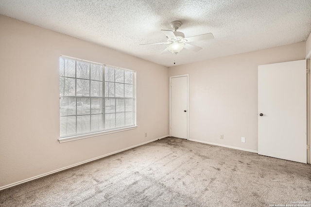 empty room with carpet, baseboards, ceiling fan, and a textured ceiling