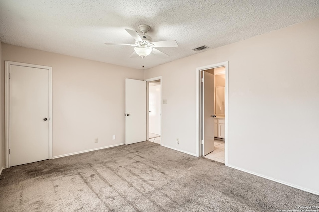 unfurnished bedroom featuring carpet floors, visible vents, a textured ceiling, ensuite bath, and baseboards