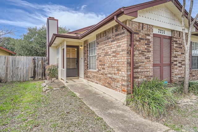 exterior space with brick siding, a chimney, and fence