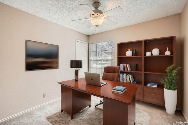 office area with a textured wall, ceiling fan, a textured ceiling, and light colored carpet