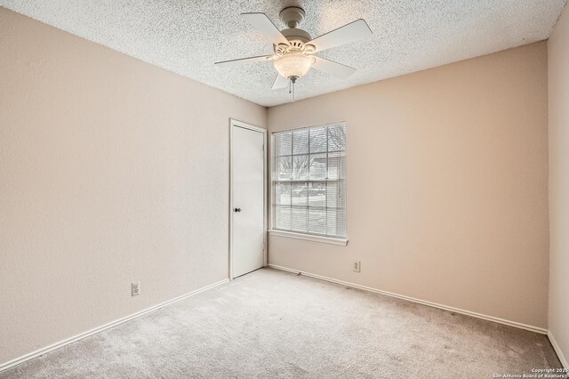 empty room featuring light carpet, ceiling fan, a textured ceiling, and baseboards