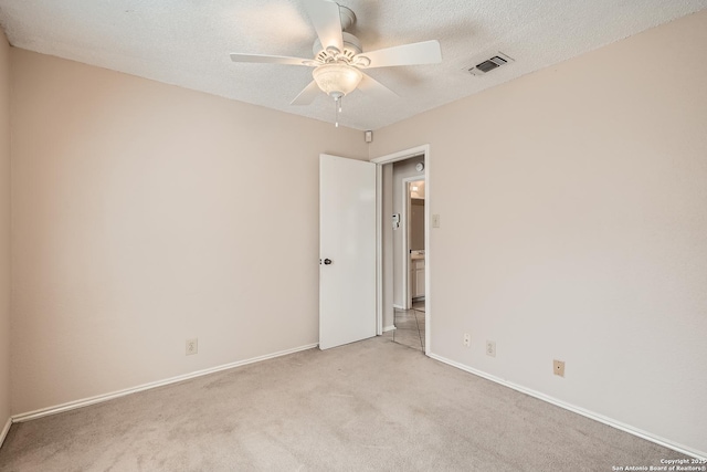 carpeted empty room with a textured ceiling, baseboards, visible vents, and a ceiling fan