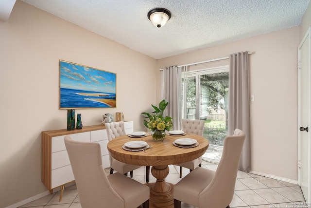 dining room featuring light tile patterned flooring, a textured ceiling, and baseboards