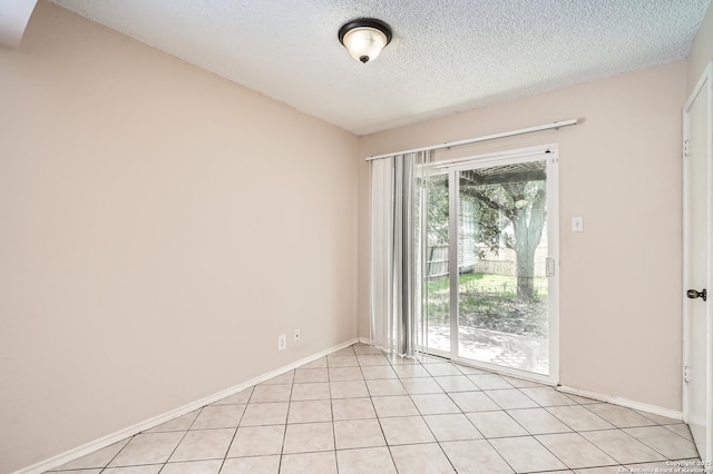 spare room with a textured ceiling, baseboards, and light tile patterned floors