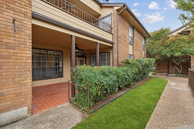 view of exterior entry with a balcony and ceiling fan