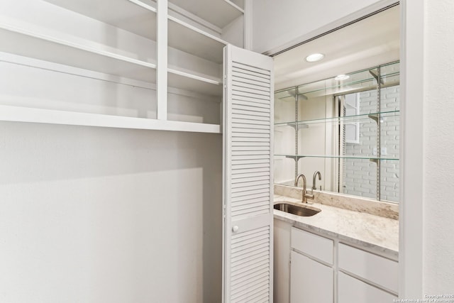 bar featuring white cabinetry, sink, and light stone countertops