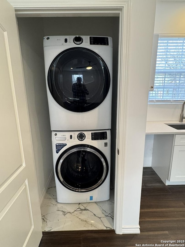 laundry area with stacked washing maching and dryer, dark hardwood / wood-style flooring, and sink