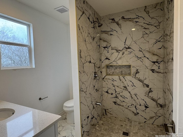 bathroom featuring vanity, toilet, and a tile shower