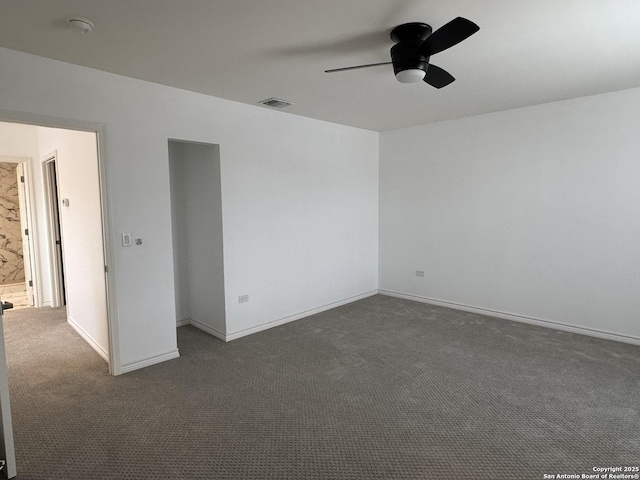 spare room with ceiling fan and dark carpet