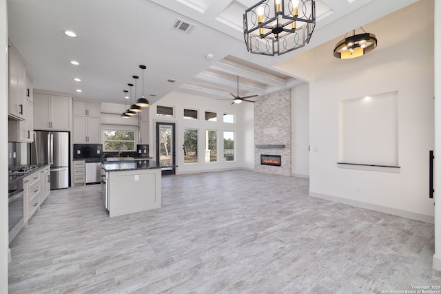 kitchen with a kitchen island, appliances with stainless steel finishes, white cabinets, and decorative light fixtures