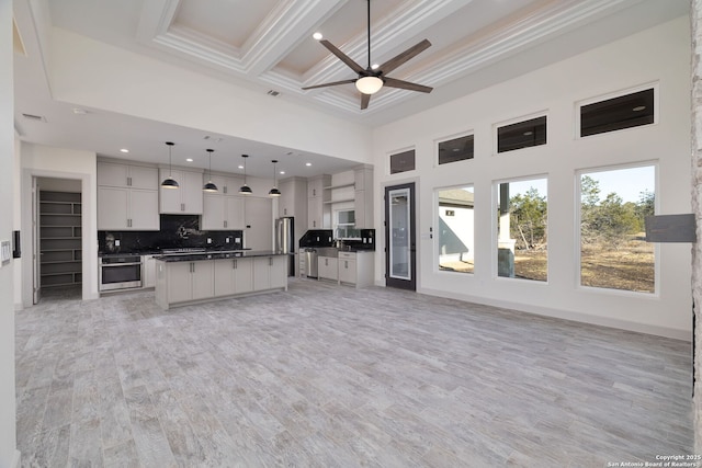 kitchen with appliances with stainless steel finishes, hanging light fixtures, backsplash, a center island, and white cabinets