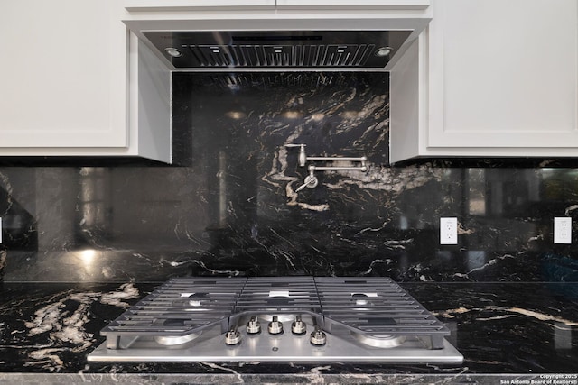 details featuring tasteful backsplash, white cabinetry, and stainless steel gas stovetop