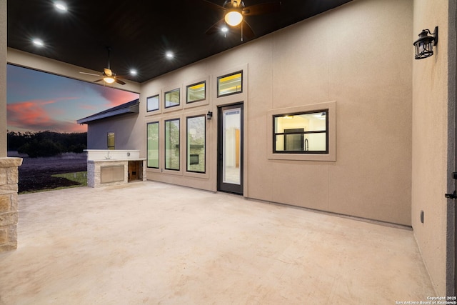 patio terrace at dusk featuring area for grilling and ceiling fan