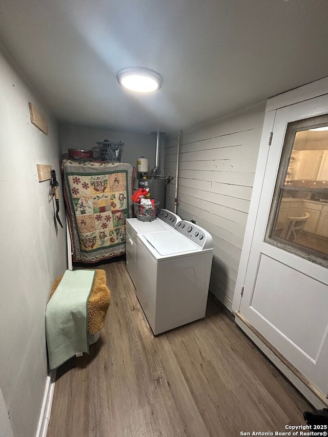 laundry room with water heater, wood-type flooring, and washing machine and clothes dryer